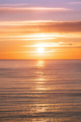 Obraz premium Sunset over Calm Ocean Water with Vibrant Orange Sky
