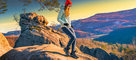 Woman running downhill on rocky mountain ridge at golden hour, insulated jacket and trail boots