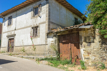 Fototapeta premium Old building with wooden doors and overgrown vegetation.