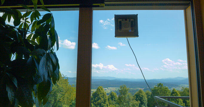 Window cleaning robot washing windows for clear view of beautiful countryside