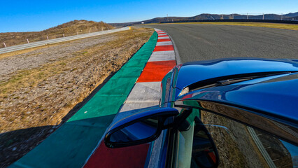 CLOSE UP: Action shot of a brand new luxury car racing on a closed circuit on a perfect sunny afternoon. Metallic blue sportscar speeds along the empty racetrack on an idyllic sunny day.