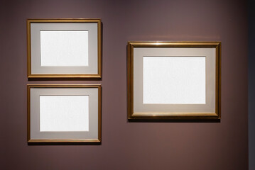 Tre cornici rettangolari con spazi vuoti per testo o immagini sono esposte su una parete marrone scuro. Queste cornici sono progettate per esporre opere d'arte o fotografie. © massimo_g