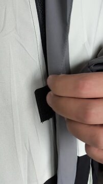 A man fastens the Velcro with the zipper of a winter jacket. Warm Winter Clothing