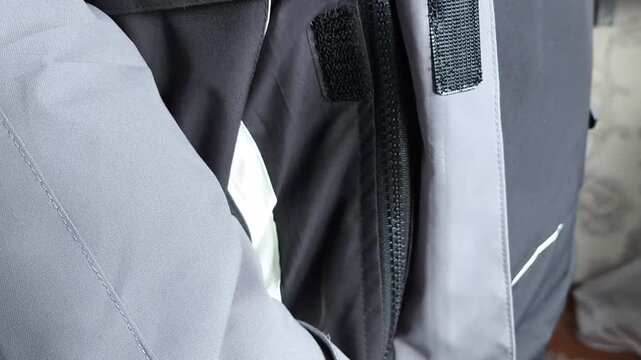 A man zips up a warm winter jacket in close-up. Down jacket for cold weather.