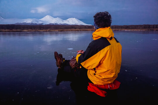 A Man on a Frozen Lake with a View of Kamchatka Volcanoes
