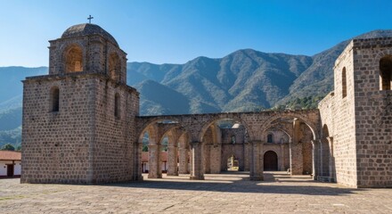 Ancient stone church ruins stand before a mountainous backdrop on a sunny day