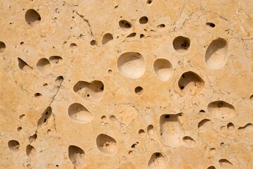 Unique beige rock formation with numerous small holes
