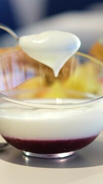 A person uses a spoon to mix and scoop cendol dessert in a ceramic bowl, under soft indoor lighting, with a close-up, steady camera angle