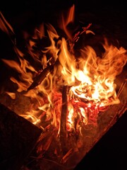 Night campfire in a winter forest. Flames and glowing embers on snow create a contrast of warmth and cold, symbolizing survival, nature connection, and calm during a winter adventure.