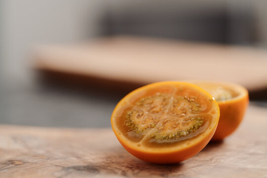 Lulo fruit sliced in halves on olive wood board on kitchen countertop
