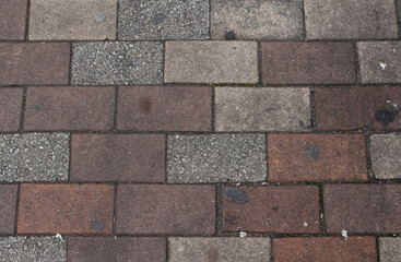 Obraz premium Texture of square paving tile. Brown, orange, gray and beige sidewalk tiles in the street. Concrete pavers close up background. 