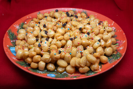 Struffoli are a typical dessert of the Neapolitan Christmas tradition, made up of small balls of sweet dough, fried and then covered in honey and colorful decorations.