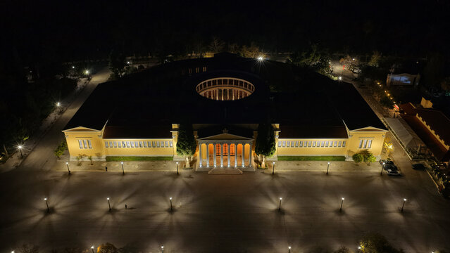 Aerial drone night shot of iconic illuminated public Zappeio hall used for events and lycabettus hill at the background , Athens historic centre, Attica, Greece