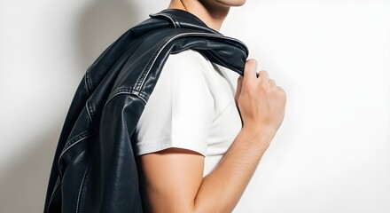 Person carrying black leather shoulder bag over denim jacket in neutral setting