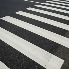 Fototapeta premium Sharp contrast black and white stripes defining a typical urban pedestrian crossing pavement markings on a textured street surface, safety, graphic, street