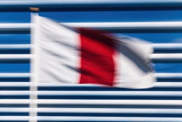 Blurred red and white cross flag waving against striped blue background