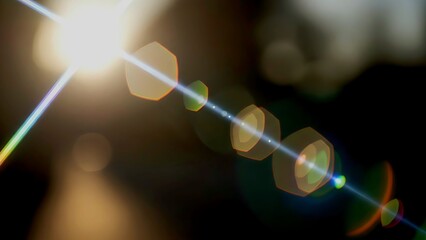 Cinematic sun lens flare with hexagonal bokeh on dark background. 