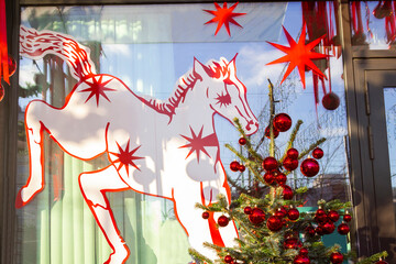 A New Year's decoration by the cafe window. A drawing of a horse and a Christmas tree with red balls.