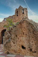 The Hermitage of the Virgin of the Rock in Mijas, Spain. This unique sanctuary is hollowed out of solid rock, featuring a stone belfry with bells and a religious statue atop the cliff