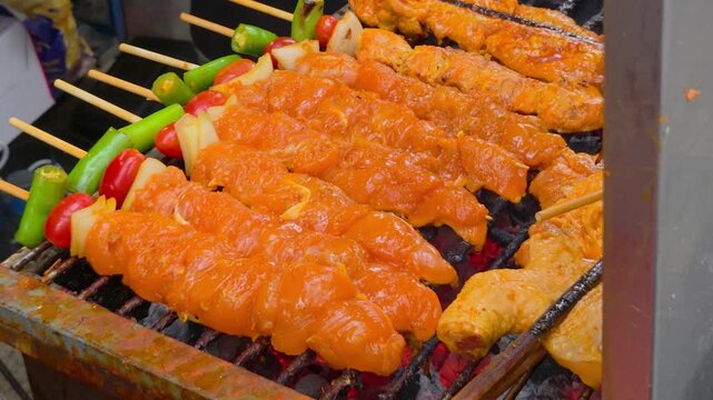 Multiple rows of seasoned chicken skewers cooking on a metal grill.