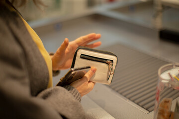 passenger preparing wallet for xray, hands fumbling small coin purse over conveyor belt, closeup of cards and clasp, bustling