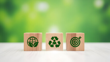 Three wooden blocks with eco friendly symbols on a table in a green background