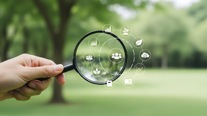 A hand holding a magnifying glass with icons floating around it in a park or garden with trees and grass