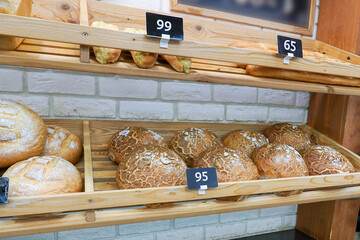 There are several loaves of wheat and rye bread on the display shelf in the store.