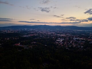 Fototapeta premium Horizon View With Rooftops And Mountains, Hilltop Vista Of Cityscape At Sunset With Distant Mountains