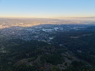 Fototapeta premium Picturesque Aerial Perspective Capturing Lush Forested Ridge And Distant Cityscape With Sunlight