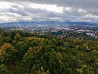 Fototapeta premium Gray Mountain View, Dull Cloudfilled Mountain Scene With Cityscape In Background And Thick Trees