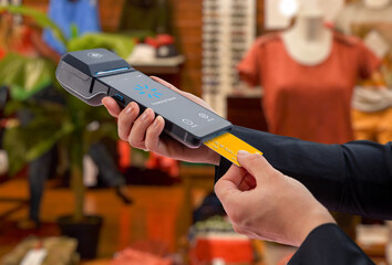 Customer inserting payment card into portable POS terminal in retail store, illustrating card transaction, in store checkout, and modern electronic payment processing
