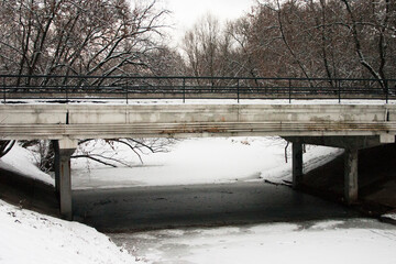 Bridge over the river in the city park under the snow in winter