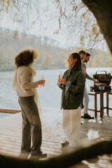 Friends enjoy a relaxing afternoon by the river with drinks and barbecue in the warm sunlight