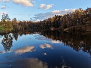 Fototapeta premium peaceful village by shimmering water, calm waters mirror colorful trees and peaceful village surroundings