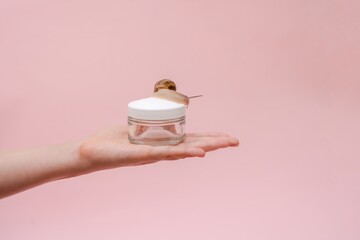 Glass cosmetics bottle with snail in woman's hand. Mockup for brand. Skin care product, spa, luxury, natural beauty cream © Antonio