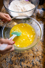 Step-by-step homemade chocolate chip cookie baking process, showing mixing wet and dry ingredients, folding in chocolate chips, and scooping raw cookie dough onto a baking sheet in a home kitchen. 