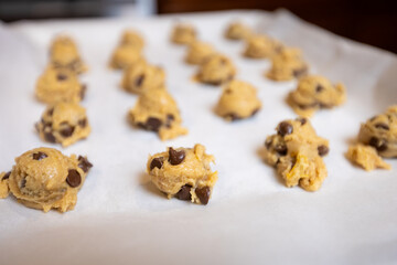 Step-by-step homemade chocolate chip cookie baking process, showing mixing wet and dry ingredients, folding in chocolate chips, and scooping raw cookie dough onto a baking sheet in a home kitchen. 