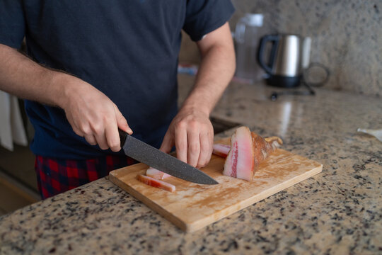 Una persona est&aacute; cortando en tiras un trozo de guanciale con un cuchillo.