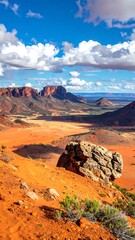 Sweeping vista of a rugged, red desert landscape under a partly cloudy blue sky