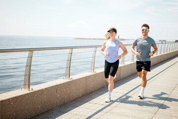 Couple jogging by the waterfront on a sunny day