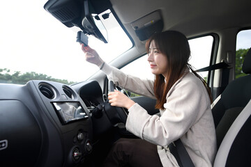 車内でドライブレコーダーを確認する若いアジア人女性