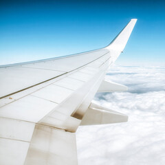 View from airplane window with wing flying above clouds during travel journey