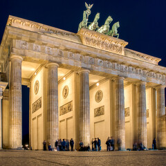 Brandenburg Gate illuminated at night with visitors in Berlin city center