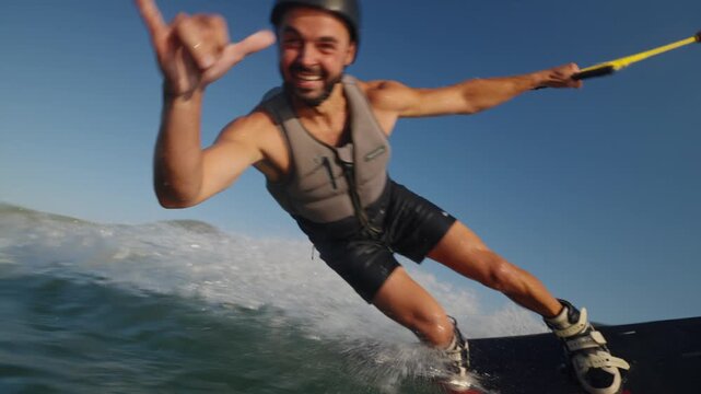 A smiling, cheerful man rides a wakeboard close to a camera on the water. Beautiful splashes. High quality 4k footage
