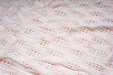 Close-up of patterned white fabric with holes