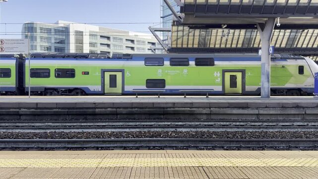 Green Train at Station: A sleek, modern green train is stationary at a bustling station, offering a glimpse into the world of urban transport and travel.