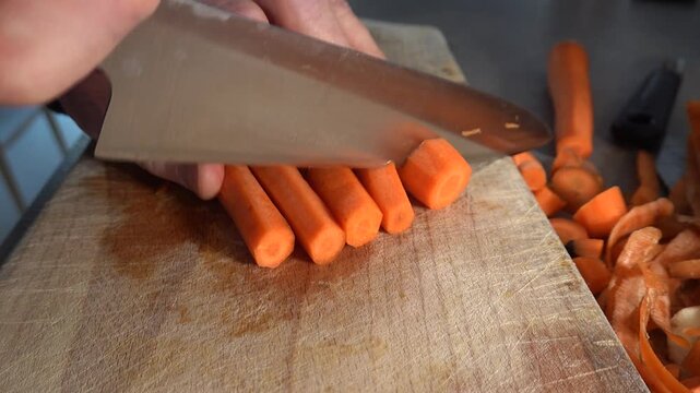 Stockholm, Sweden A cook chops and slices carrots in a kitchen on a wooden board.