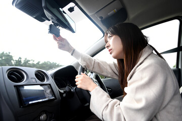 車内でドライブレコーダーを確認する不安そうな表情の若いアジア人女性