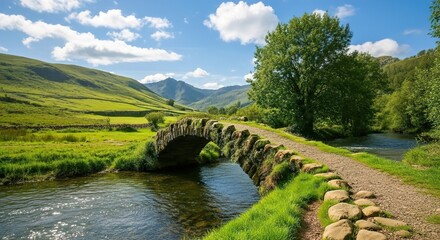 Fototapeta premium Ancient Stone Bridge Over River in Lush Green Valley – Scenic Countryside Landscape